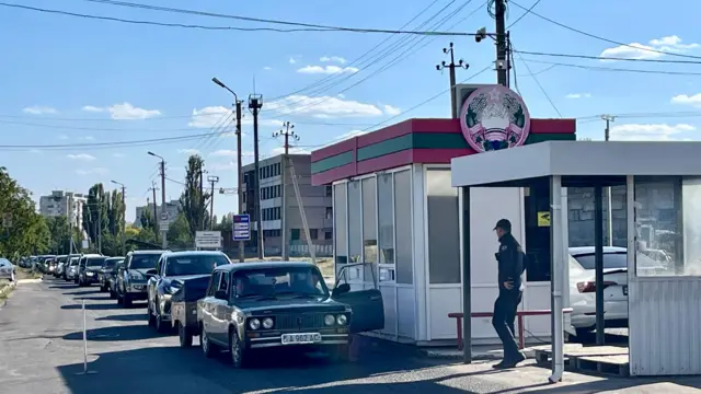投票所の前の通りに車が並んでいる。職員らしき人物もいる
