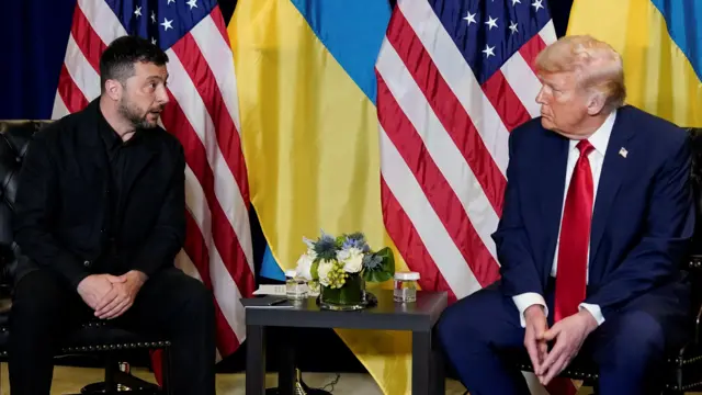 両大統領が小さなテーブルを挟んでいすに座り目線を合わせている。ゼレンスキー氏はダークカラーのジャケットにシャツ、トランプ氏は紺色のスーツに白いシャツ、赤いネクタイを身に着けている