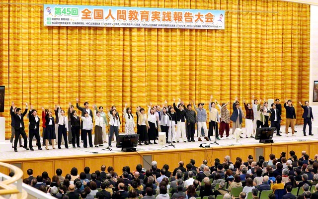 全国人間教育実践報告大会で青年教育者が合唱。小学校教諭の田中大輝さん、保育士の蘆田菜々さんが元気に司会を務めた（北海道池田講堂で）