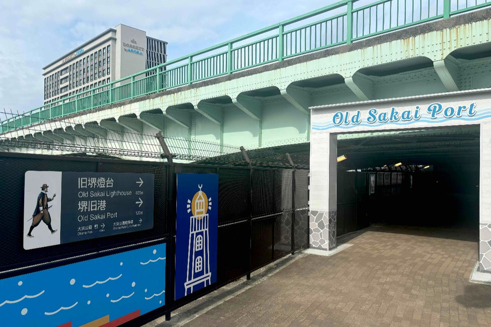 entrance to the old sakai port area with directional signs and a modern building in the background