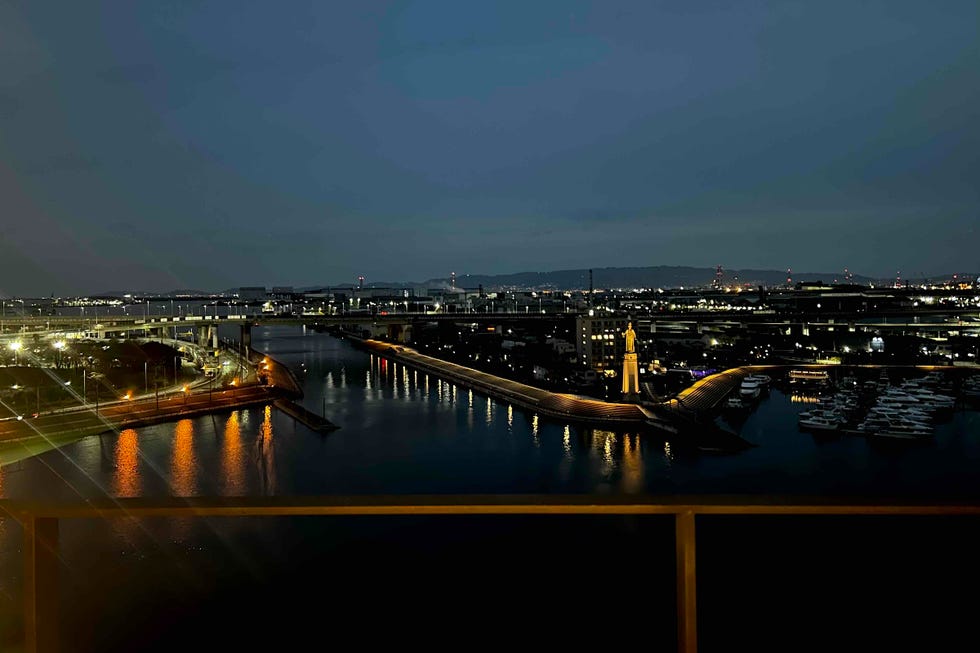 nighttime view of a waterfront area featuring buildings a statue and a marina