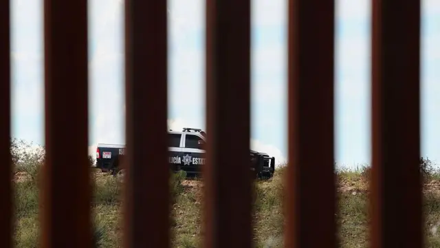 アメリカとメキシコの国境に設置されたフェンス越しに、メキシコのパトカーが見える