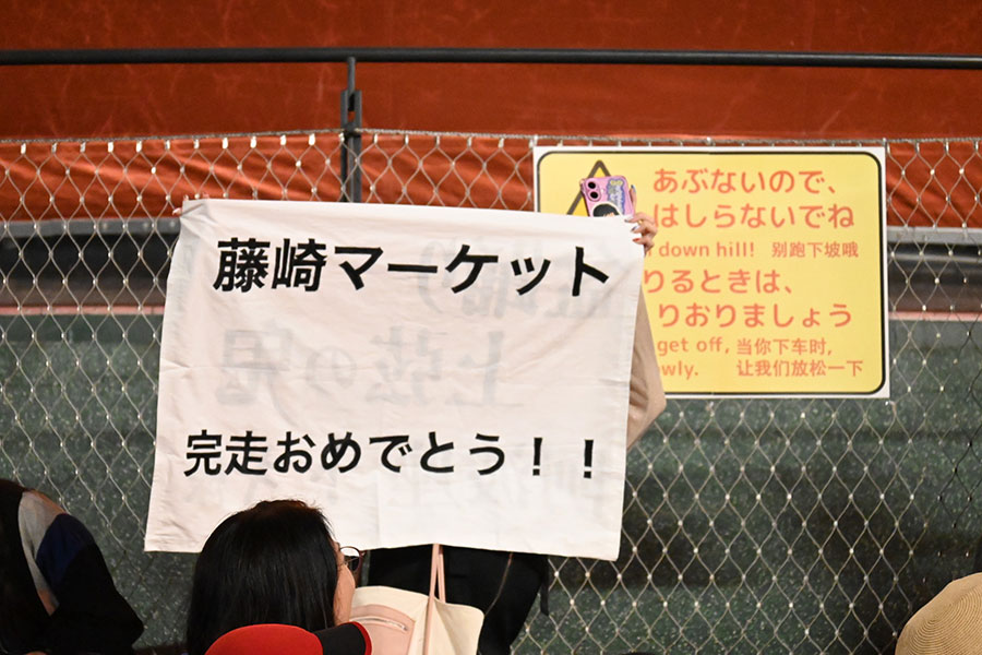 「盆踊りのアシタ」のフィナーレ、盆踊り神４として盛り上げに貢献した藤崎マーケットにメッセージを掲げる人も（10月13日／大阪・関西万博）