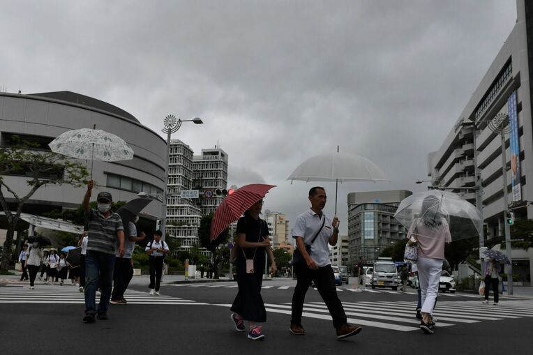 梅雨空の下、傘を差して交差点を行き交う人たち＝5月22日午前10時57分、那覇市久茂地