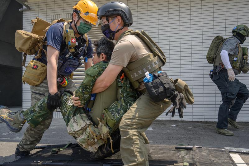 訓練で、負傷兵役の男性を運ぶ2人の男性