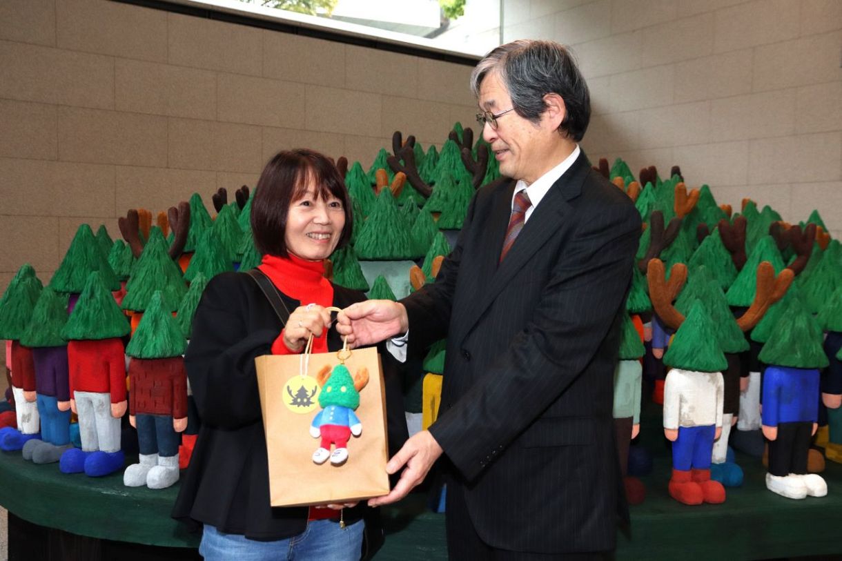１万人目の入場者となり、守安館長（右）から記念品を贈られる嶋田さん