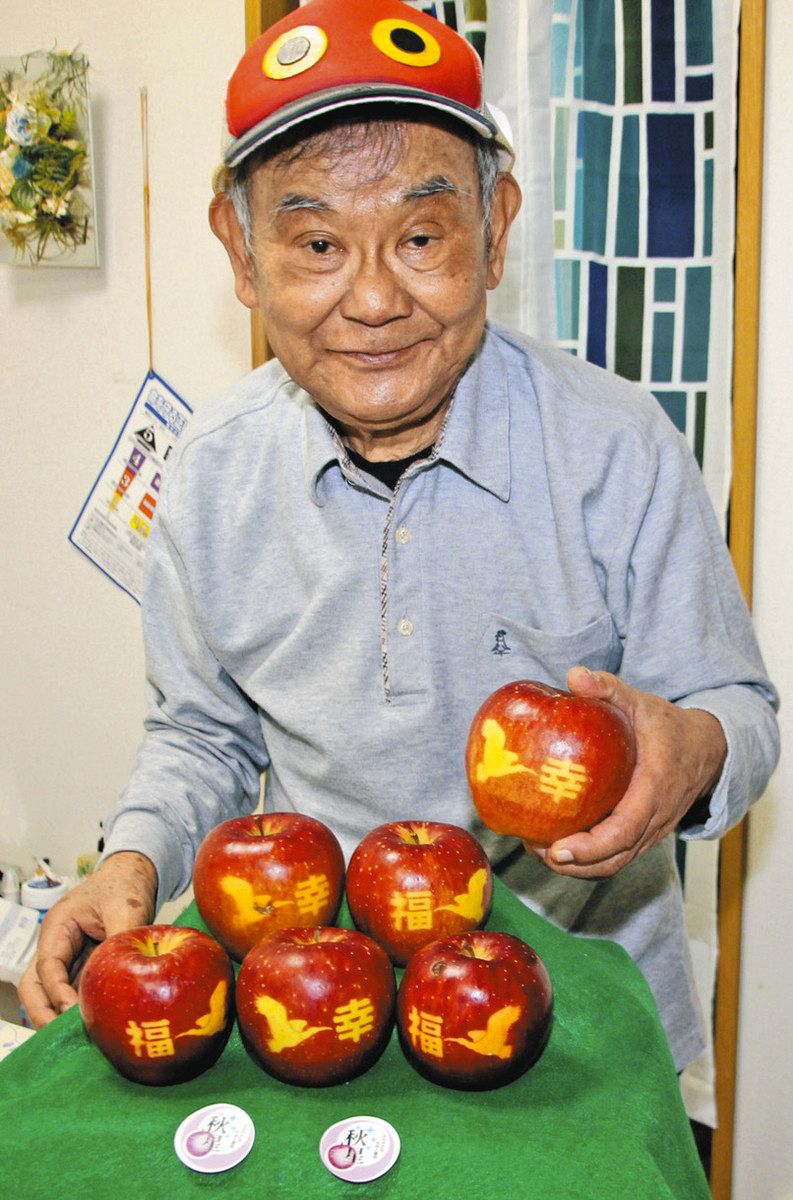 トキの絵柄のリンゴを手にする岡本孝二さん＝金沢市内で
