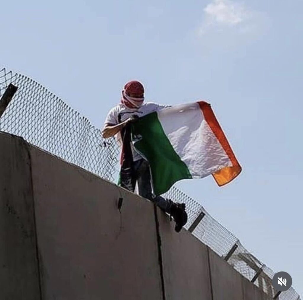 イスラエルのアパルトヘイトの壁を越えてトリコロールを飛ばすパレスチナ人の若者が目撃される