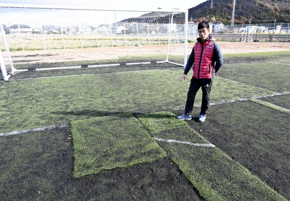 つぎはぎ状態になった人工芝の危険性について語る横江監督（滋賀県野洲市で）