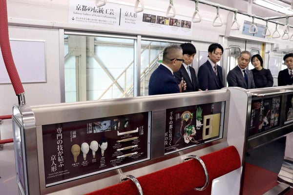 京人形など京都の伝統工芸をあしらった新車両を見学する関係者たち（伏見区で）