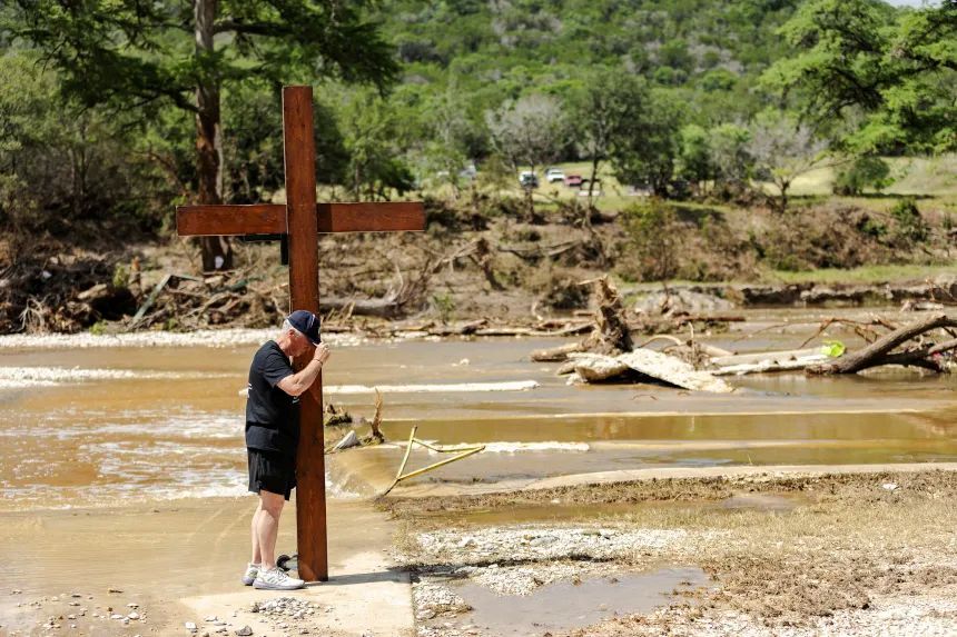 25年7月8日、鉄砲水が起きたテキサス州イングラムの川の岸に佇み、祈りを捧げる/Jim Vondruska/Getty Images