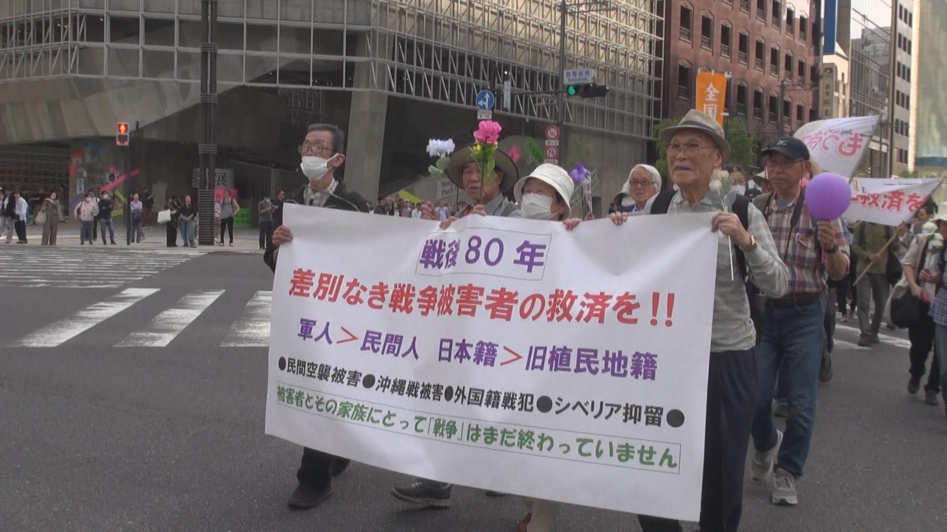 2025年４月「差別なき救済を！！」と銀座で訴える西倉勝さん（右端100歳）