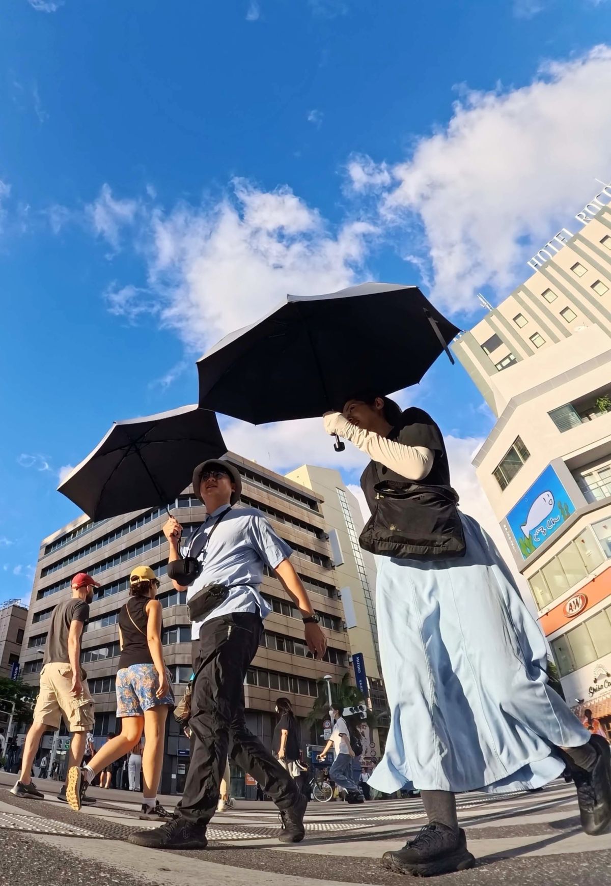 沖縄地方でことし初めての「猛暑日」となる35.0度を観測した10月2日。暑さが続き、夕方も日傘を差す歩行者=同日午後5時20分、那覇市久茂地(喜屋武綾菜撮影)