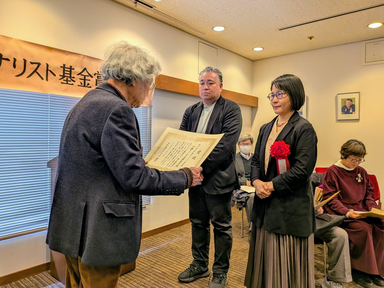 鎌田慧代表委員（左）から平和・協同ジャーナリスト基金賞を受ける新垣綾子記者と吉田伸記者＝１３日、東京・内幸町の日本プレスセンタービル