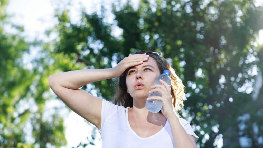 Young woman having hot flash and sweating in a warm summer day