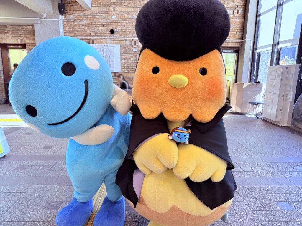 【高知市】かわいすぎる…!くろしおくんグッズがもらえる「よさぶんひろめ隊」に参加してみた | 号外NET 高知市 よさぶんひろめ隊のマスコットを持っている高知家のくろしおくんと南国市のシャモ番長