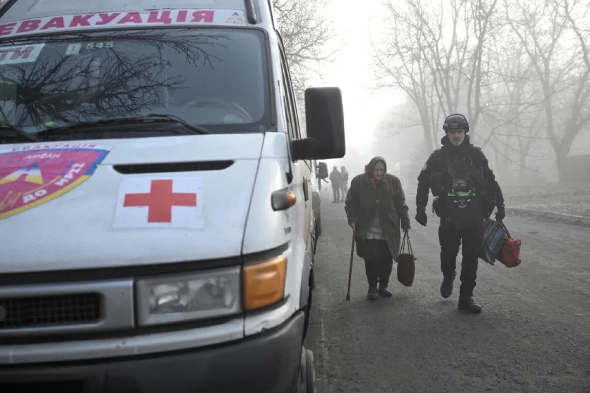 最前線の町フリャイポレから避難する女性を支援する警官=2025年11月14日、ザポリージャ州/Stringer/Reuters