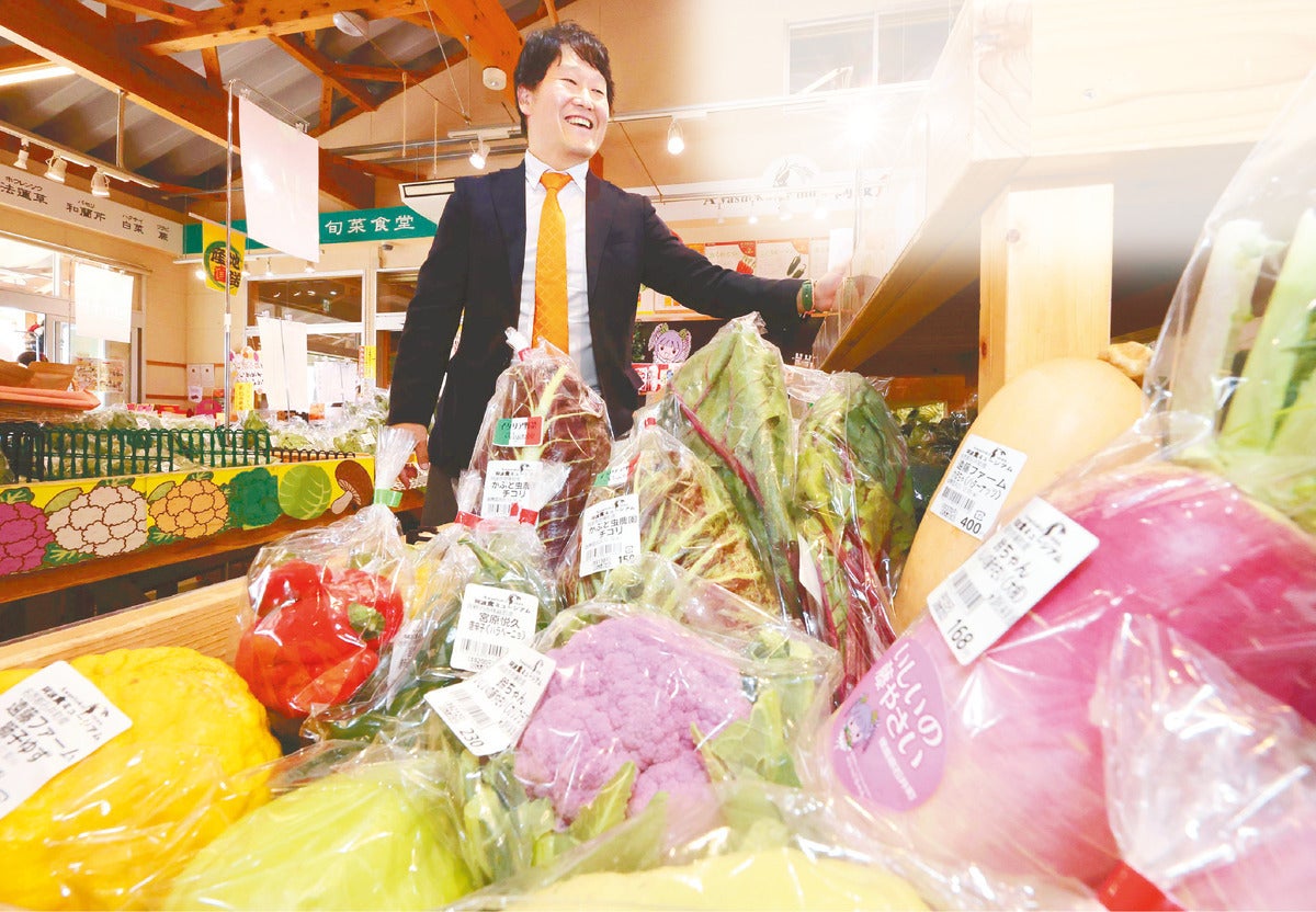 紫ダイコンなどが並ぶ売り場で希少野菜の魅力を語る小川さん（徳島県石井町で）
