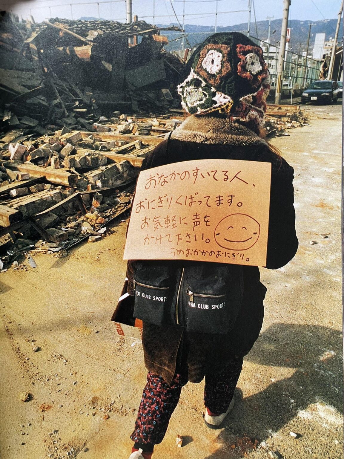 1995年1月21日 神戸市東灘区御影本町、瓦礫の街でおにぎりを配って歩く女性。朝日新聞「報道写真全記録 阪神大震災」より