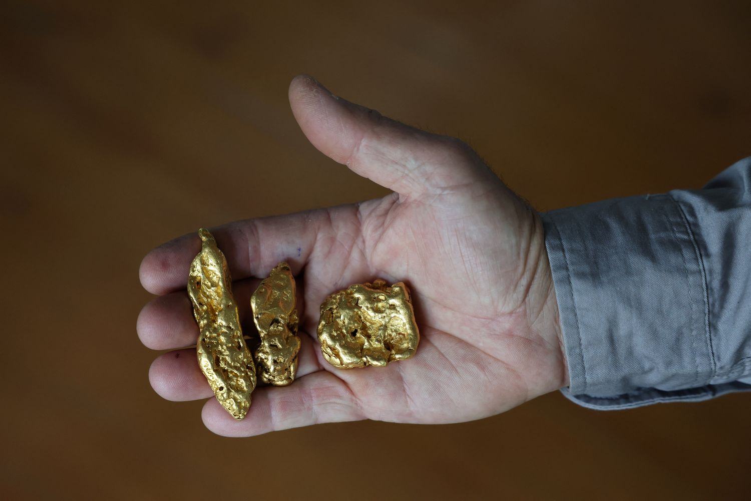 A shop worker poses holding three gold nuggets at The Gold Centre store, in Maryborough, Australia, November 28, 2025. (Reuters)