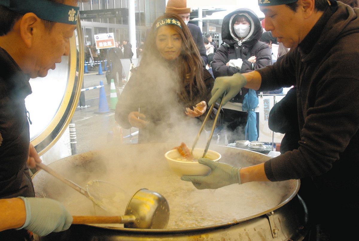 「カニ入り海鮮富山湾鍋」を提供する富山湾食堂の人たちと待ちわびる人＝富山市の富山駅南口広場で

