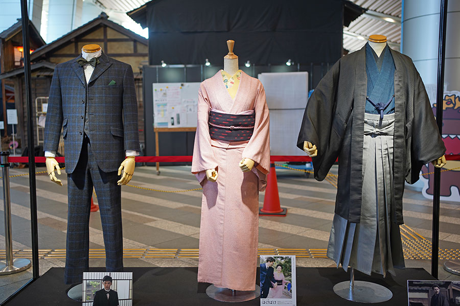 「『ばけばけ』セット公開」で展示されている、英語教師・錦織（吉沢亮）、トキ（髙石あかり）、ヘブン（トミー･バストウ）の衣装。奥には、セットが建て込まれている（2月19日撮影／Lmaga.jp）