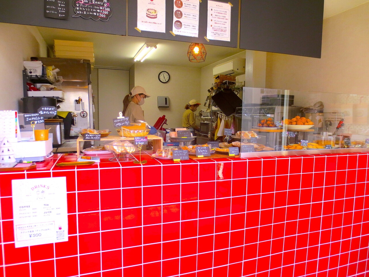 赤いタイルが印象的なカウンター。厨房では2人がお菓子作りをしています。