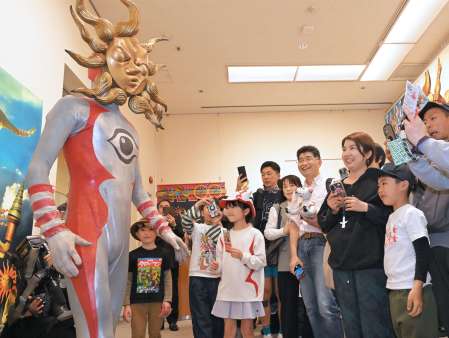 来場者の記念撮影に応じるタローマン＝２０日、鹿児島市立美術館
