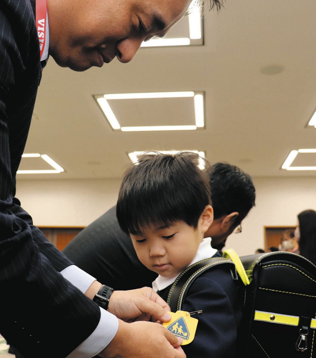 新小学１年生に黄色いワッペンを着ける銀行、保険会社の代表者ら＝県警本部で
