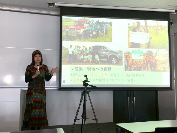 岩井雪乃准教授がスクリーン前で登壇し、講演している。