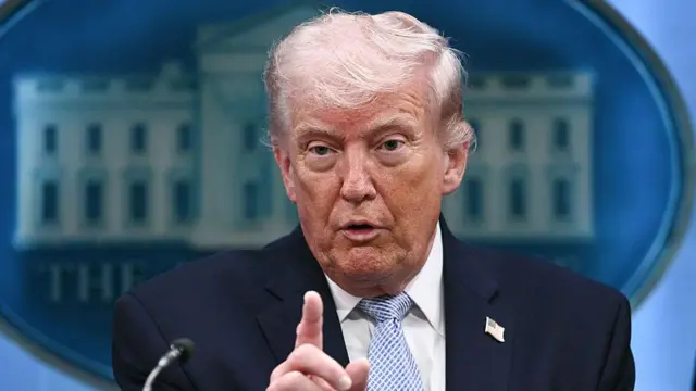 演壇のマイクの前で記者会見するトランプ米大統領。右手の人差し指を挙げている