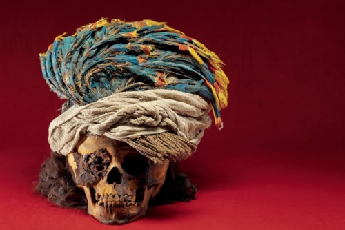 インコの色鮮やかな羽根をあしらった頭飾りをかぶる生け贄にされた子どもの頭骨。その豪華な装飾品から、高貴な家の生まれだったと考えられる。（PHOTOGRAPH BY REBECCA HALE,NGM STAFF）