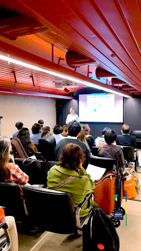 4月10日、駐日ブラジル大使館およびギマランイス・ホーザ文化院は、イベロアメリカ音楽振興プログラム（Ibermúsicas）を通じて日本でアーティスト・イン・レジデンス事業に参加しているギタリスト、ファブリシオ・マットスを迎え、講演・ワークショップ「リズムを巡る旅」を開催しました。会場には、ブラジル民衆舞踊のリズムに浸るプログラムを目当てに、熱心な参加者が集まりました。 ワークショップでは、カリンボー、フレーヴォ、カチーラ、ミロンガ、ショーロといった多彩なジャンルが取り上げられ、ボディパーカッション、グラフィック表現、楽器演奏を組み合わせた、活気あふれる交流が行われました。 最後には、バンドリン奏者・林真衣が特別出演し、日本の楽曲「春よ、来い」をブラジルのリズムで再解釈した参加型の演奏が行われ、両国をつなぐ音楽の架け橋となるひとときとなりました。 .
No último 10 de abril, a Embaixada do Brasil em Tóquio e o Instituto Guimarães Rosa receberam o violonista Fabricio Mattos, em residência artística no Japão pelo programa Ibermúsicas, para a palestra e oficina “Uma Viagem através do Ritmo”. O evento reuniu um público engajado em uma imersão nos ritmos das danças populares brasileiras. Ao longo do encontro, foram explorados gêneros como carimbó, frevo, catira, milonga e choro, combinando percussão corporal, linguagem gráfica e prática instrumental em um ambiente de troca dinâmica. O momento final trouxe uma releitura coletiva da canção japonesa “Haru Yo, Koi”, reinterpretada em ritmos brasileiros, criando uma ponte musical entre os dois países, com participação especial da bandolinista Mai Hayashi. | 駐日ブラジル大使館