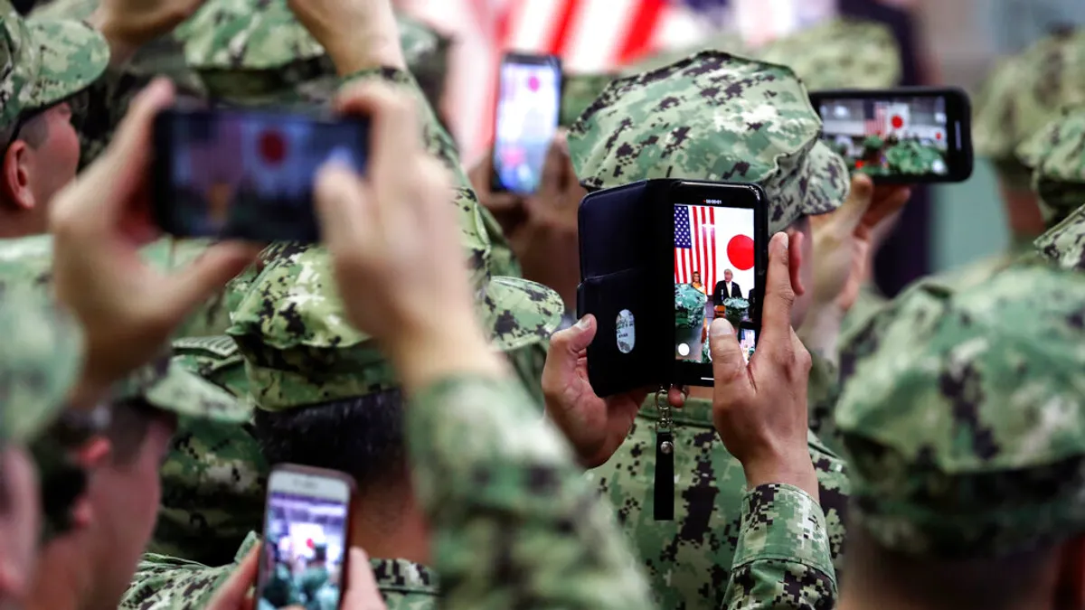 28日、横須賀基地で在日米軍を視察する米大統領・トランプ氏。スマートフォンで同氏を撮影する米兵ら（AP通信）