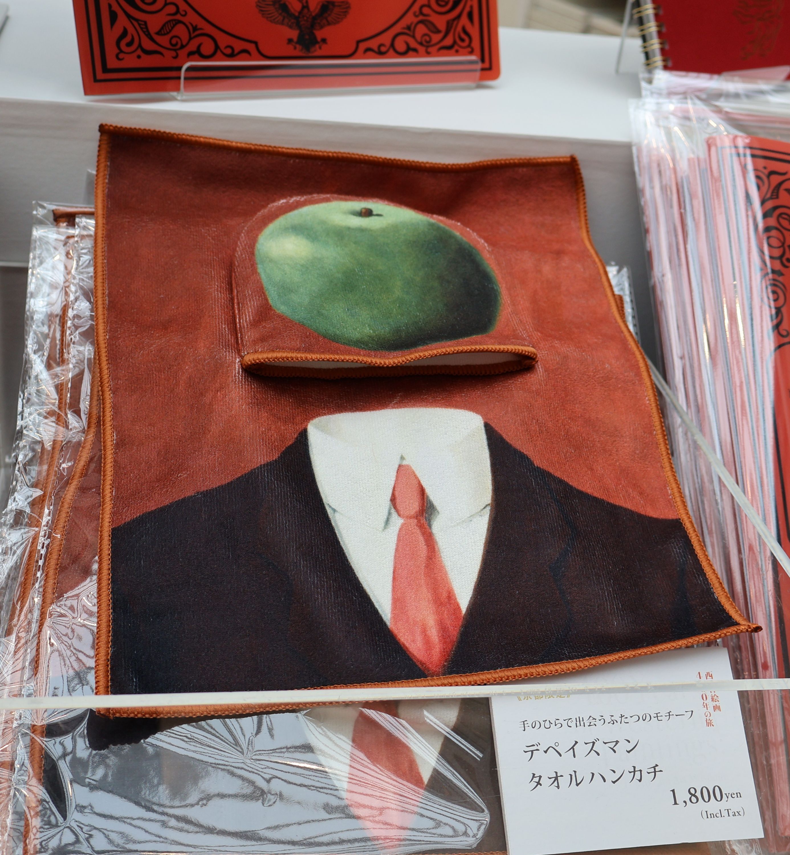 フェリシモ「ミュージアム部」とコラボしたルネ・マグリットの「観念」のタオルハンカチ。リンゴのポケット部分に、人間の部分をたたんで、収納することができる