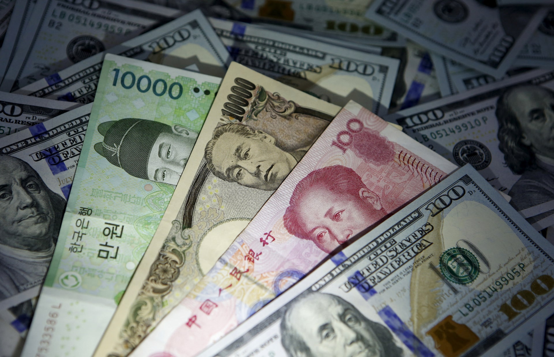 FILE PHOTO:韓国ウォン、中国元、日本円の紙幣が米国の100ドル紙幣に描かれている(ソウルで撮影)。