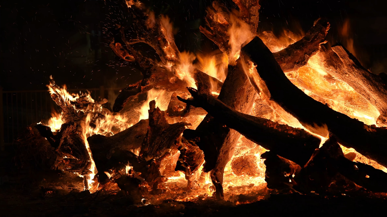 キプロス、ペゲイアの伝統的な正統派イースターのお祝いの際に巨大な丸太が燃える大きなかがり火。炎を見守る人々のシルエット