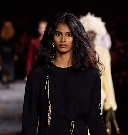 model walking the runway in a black outfit with decorative elements