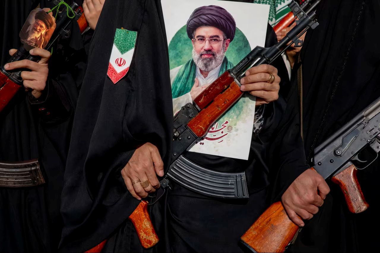 ライフルを携える女性の胸元にはイランの新たな最高指導者モジタバ師の肖像が/Majid Saeedi/Getty Images