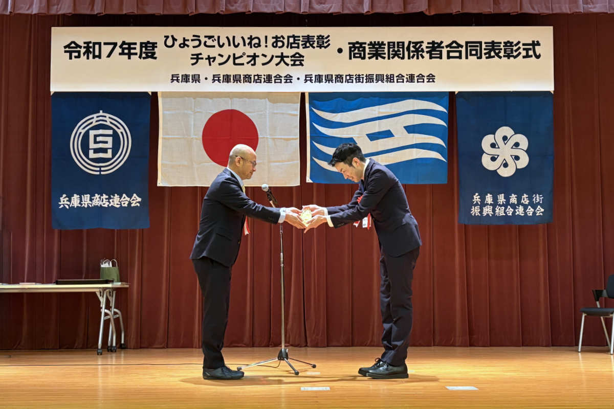 小林拓哉部長（左）からトロフィーを授与される「Ryu Cafe」の藤井俊輔さん