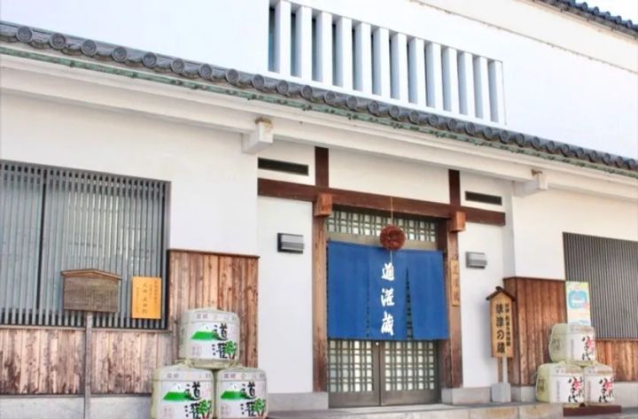 道灌蔵と書かれた青い暖簾が掛かる白漆喰造りの酒蔵正面玄関。入口両側に道灌銘柄の菰樽が複数積まれている