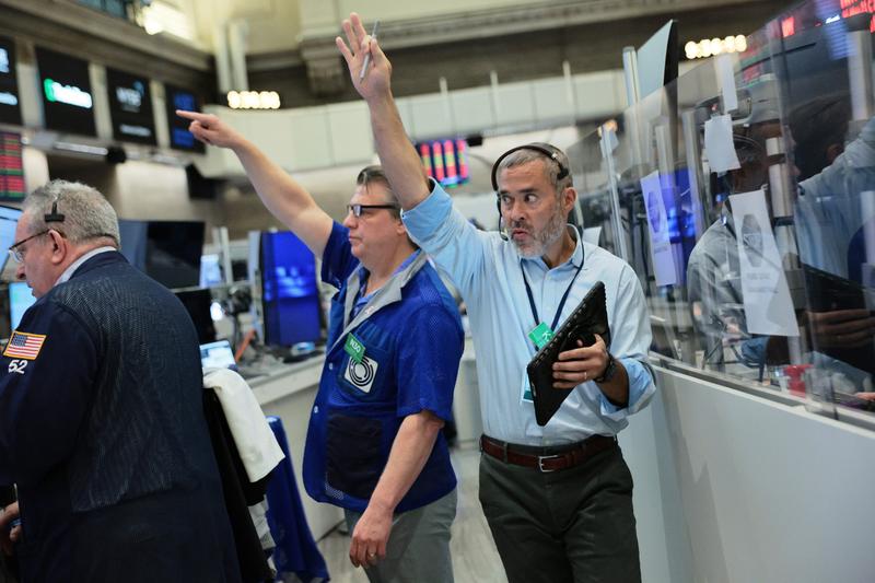 Two traders at the NYSE raising their hands in the air and pointing