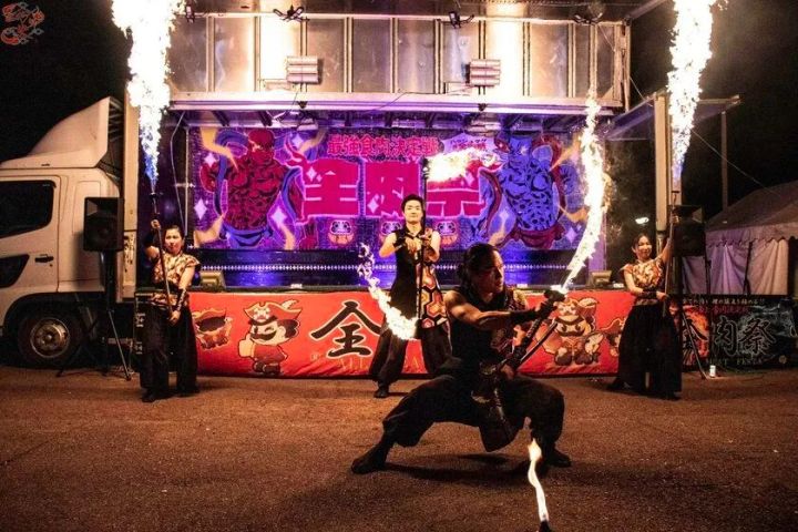 全肉祭会場ステージ前で行われた夜間ファイヤーパフォーマンスの実写写真。4名の演者が炎を操り、背後に全肉祭ロゴ入りトラックステージと火柱が写る