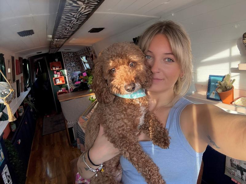 A woman takes a selfie in a narrowboat holding her dog.