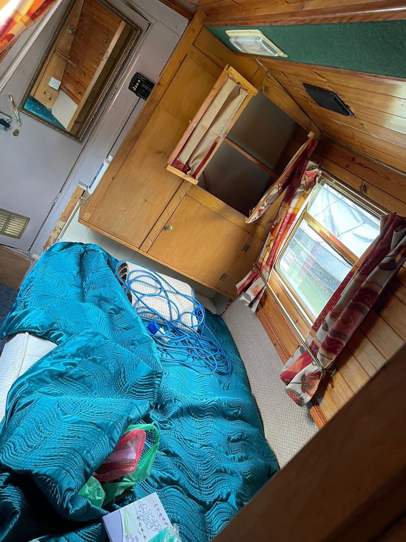 The interior of a boat with a wooden interior and a bedding area.