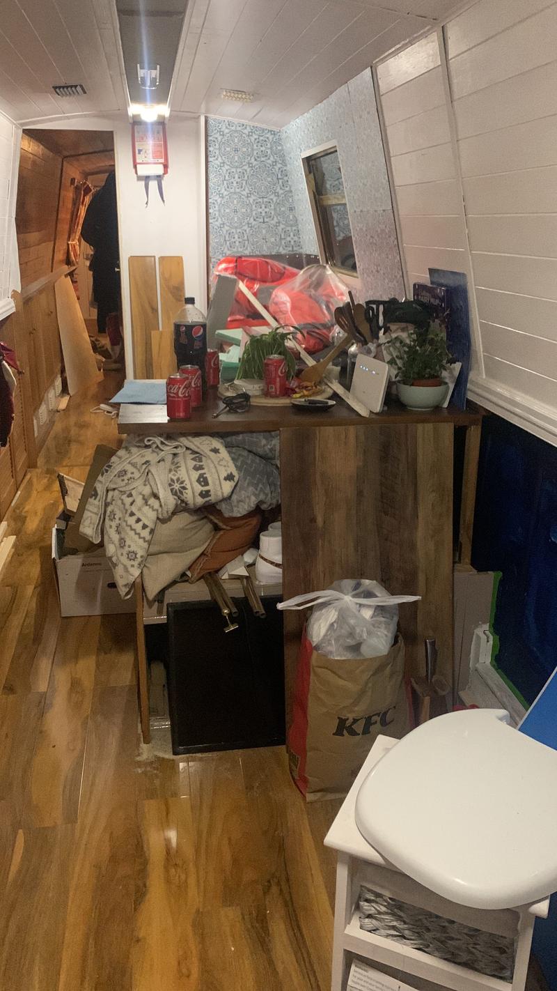 The interior of a boat with white walls. A large pile of stuff cits in the center of the room.