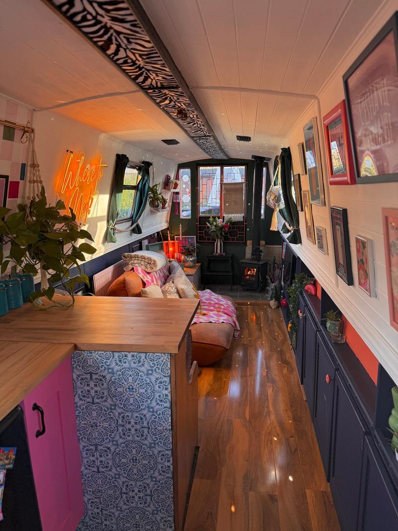 The inside of a narrowboat with a living area at the back and a kitchen at the front.