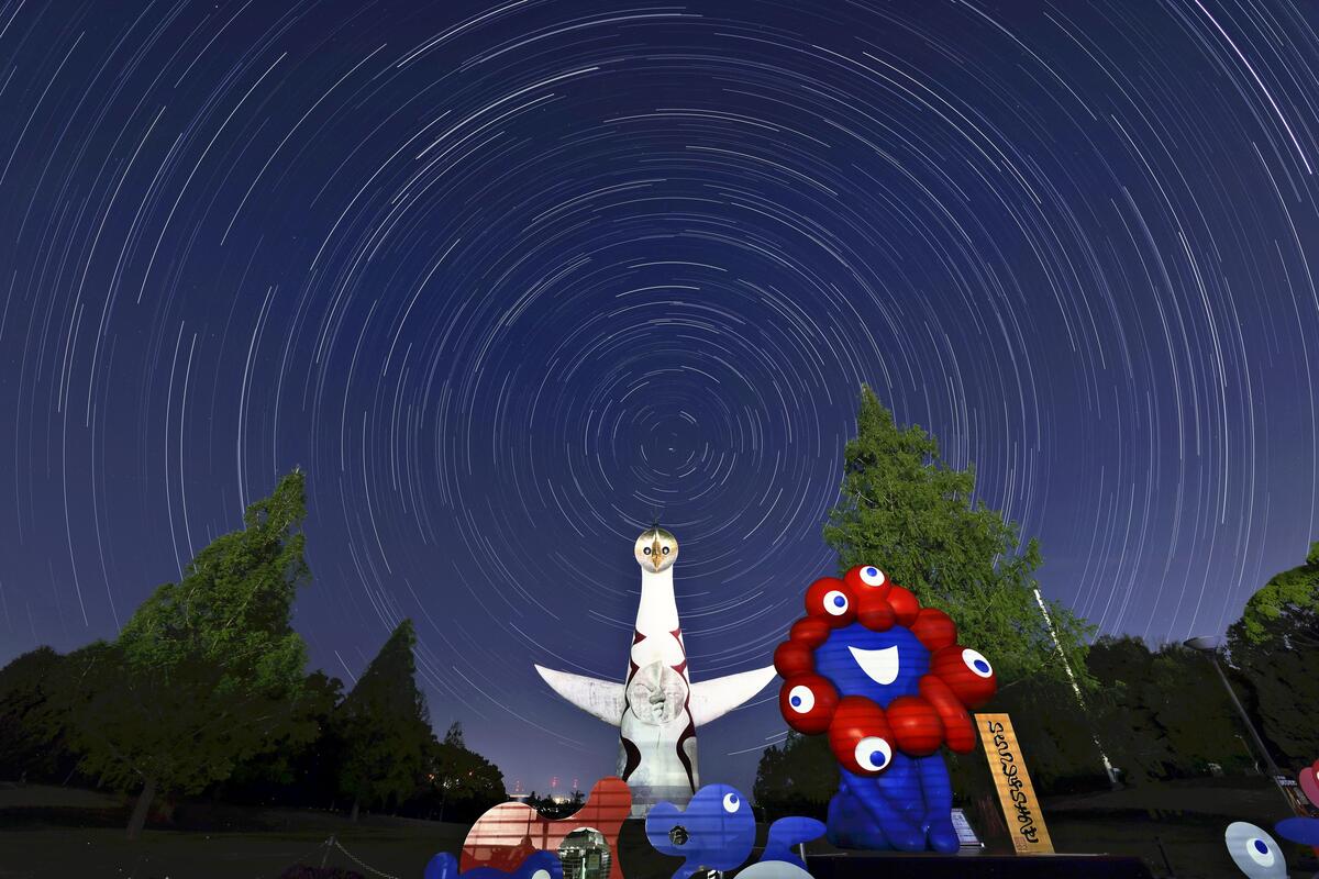 ミャクミャクのモニュメント（手前）と太陽の塔の頭上に広がる星空（大阪府吹田市の万博記念公園で）＝原田拓未撮影