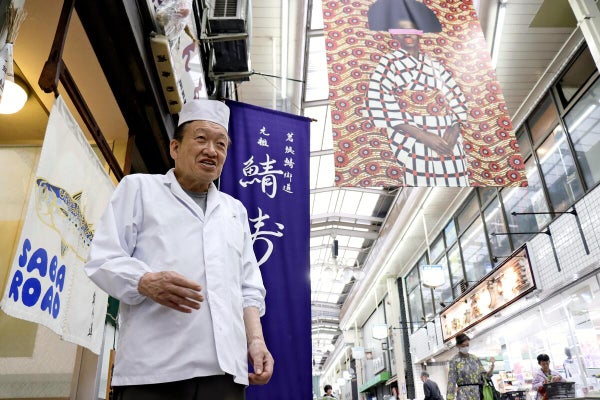 「来店頻度を高めたい」と語る梅垣さん。アーケードには国際写真祭の会期中、作品が展示された（京都市上京区で）