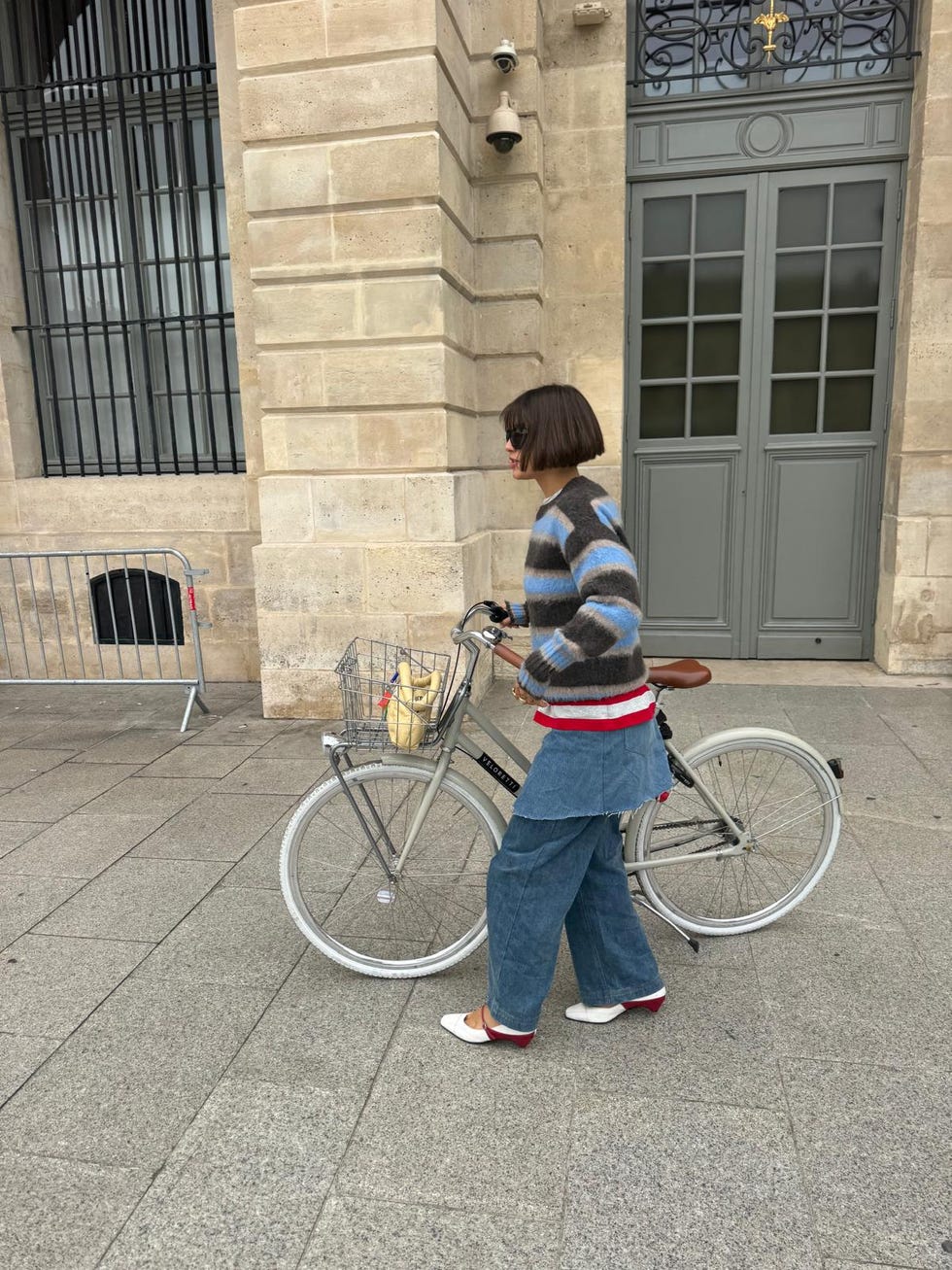 person walking a bicycle beside a building
